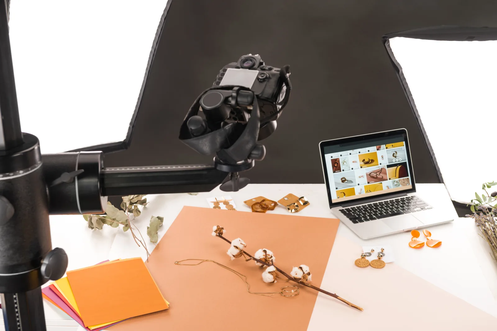 Fotostudio-Aufbau: Kamera am Schwenkarm über einem Tisch mit Schmuckstücken, daneben ein Notebook mit der Bildübersicht